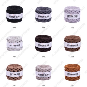 May include: Nine balls of cotton yarn in various colors, including black, gray, beige, brown, and tan. Each ball has a label that reads "Cotton Club Premium T-Shirt Yarn".