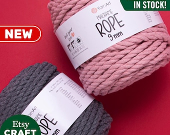 Op de afbeelding: Twee spoelen van 9 mm macramé touw, een in roze en een in grijs. De spoelen zijn gelabeld "YarnArt Macrame Rope 9 mm". De tekst "ALL COLORS IN STOCK!" staat in groene letters op een witte achtergrond.
