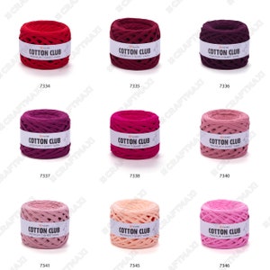 May include: Nine balls of yarn in various shades of pink and red. The yarn is made of cotton and is labeled "Cotton Club Premium T-Shirt Yarn".