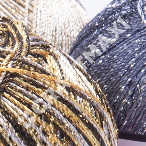 Op de afbeelding: Close-up van drie spoelen garen met metallic draden. Het garen is zilver, goud en zwart met een glinsterende afwerking.