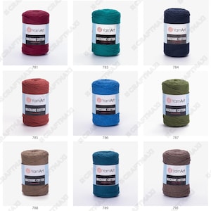 Op de afbeelding: Negen spoelen macram&eacute; katoenen garen in verschillende kleuren, waaronder rood, blauw, groen, bruin en grijs. Elke spoel is gelabeld met "YarnArt Macrame Cotton".