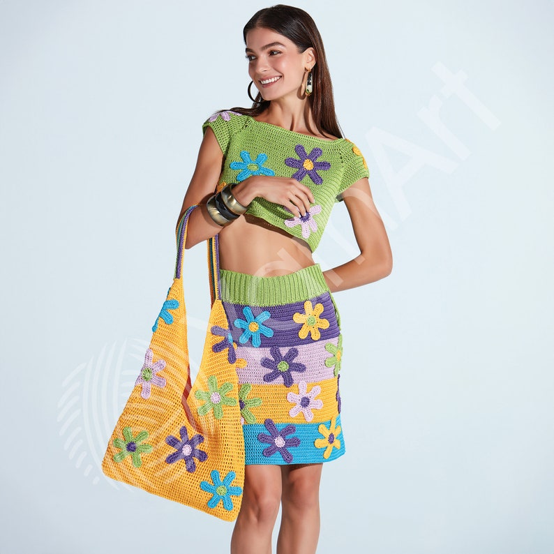 May include: A crocheted outfit with a green and purple skirt and a matching green top with colorful flower accents. The outfit is paired with a yellow crocheted bag with colorful flowers.
