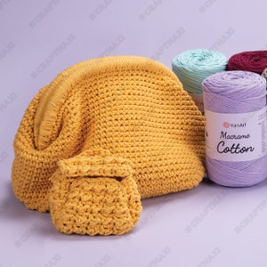 Op de afbeelding: Een gele gehaakte tas en een kleinere bijpassende tas. De tas is gemaakt van een dik katoenen koord en heeft een afgeronde vorm. Het garenlabel luidt "YarnArt Macrame Cotton".