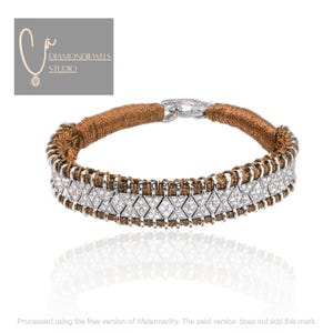 Può includere: Un bracciale di lusso con un cinturino intrecciato marrone e una sezione argentata ornata di diamanti. Il bracciale ha una chiusura argentata ed è presentato su sfondo bianco. Il marchio "DIAMONDJEWELS STUDIO" è visibile.