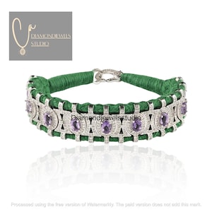 Puede incluir: Un collar de cordón verde con un cierre plateado y una banda decorativa con piedras preciosas ovaladas moradas y pequeñas piedras blancas. El collar tiene el texto "Diamondjewelsstudio".