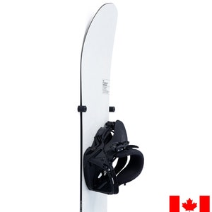 May include: A white snowboard with black bindings mounted on a wall. The snowboard has the text "The All Mountain Super Shape" printed on it.