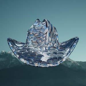 Puede incluir: Sombrero de vaquero bordado con un diseño de plumas en tonos azules, blancos y dorados. El sombrero tiene una forma clásica con ala y copa. Un accesorio elegante para un look western.
