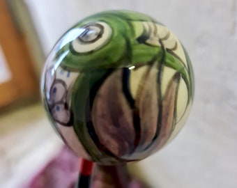 La petite boule "Fleur Violette" est faite à la main et unique. La céramique est cuite à partir d'argile légère, peinte et émaillée à la main.