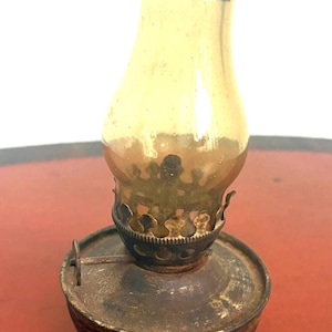 Vintage miniature oil lamp or hurricane finger lamp with an amber glass shade.