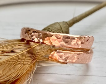 Könnte beinhalten: Zwei gehämmerte Kupferringe, einer etwas größer als der andere, liegen übereinander. Die Ringe haben eine warme Roségoldfarbe und eine strukturierte, gehämmerte Oberfläche.