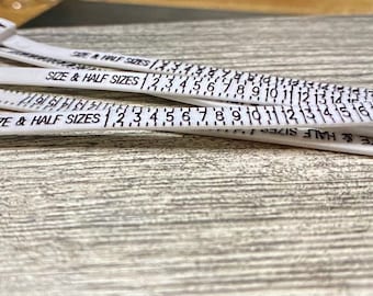 May include: Four white plastic ring sizers with black markings. The sizers are labeled "Size & Half Sizes" and show numbers from 1 to 17.