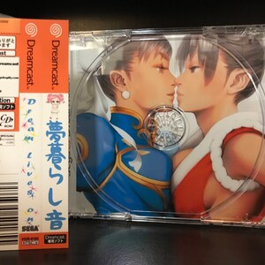 May include: Dreamcast video game case with a pink and orange Dreamcast logo. The game title is "Dreamcast. 夢蒼いし音" in Japanese. The game disc art features two women in a close-up portrait.