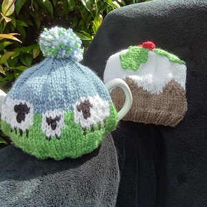 May include: Two knitted teapot cosy covers. One is blue with white sheep and green grass. The other is brown, white and green and resembles a Christmas pudding.