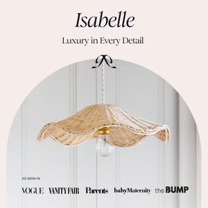 May include: A woven rattan pendant light with a scalloped edge, featuring a clear lightbulb and gold-toned hardware. The light is suspended from a white rope and a black bow. The text "Isabelle" and "Luxury in Every Detail" are at the top.