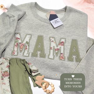 May include: A light grey crewneck sweatshirt with the word MAMA appliqued in olive green and floral fabric. Included are olive green and floral baby clothing items, a wooden toy, and a tag reading ZC ZARA CREATIONS. Text reads TURN THEIR MEMORIES INTO YOURS.