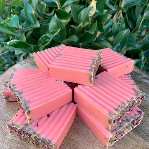 May include: A stack of pink soap bars with green and pink flecks. The soap bars have a ridged texture.