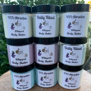 Pode incluir: Uma cole&ccedil;&atilde;o de oito potes de manteiga corporal batida com tampas pretas. Cada pote tem um r&oacute;tulo com o texto "XXX Attraction" ou "Daily Ritual" e "Whipped Body Butter". Os r&oacute;tulos tamb&eacute;m apresentam um gr&aacute;fico de uma mulher e uma lua crescente.