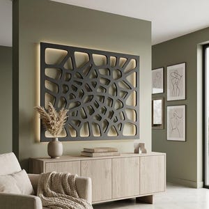 May include: A rectangular black wall panel featuring an intricate, organic, web-like cutout pattern. The panel is mounted on a wall and backlit, creating a soft glow around its edges. The design consists of irregular, interconnected shapes.