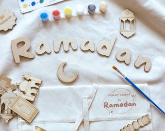 May include: A craft kit for kids to paint wooden decorations for Ramadan. The kit includes a canvas bag, paint, brushes, and wooden cutouts of crescent moons, lanterns, and the word "Ramadan" in Arabic.
