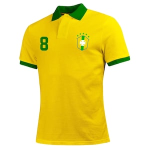 Op de afbeelding: Een geel poloshirt met groene bies en een groen-wit embleem op de borst. Het nummer 8 is gedrukt op de linkerzijde van het shirt.