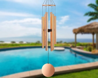 May include: A copper wind chime with multiple tubes hanging from a circular frame. The chime has a round, copper-colored clapper at the bottom.