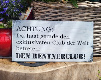 May include: White wooden sign with black text that reads "ACHTUNG: Du hast gerade den exklusivsten Club der Welt betreten: DEN RENTNERCLUB!"