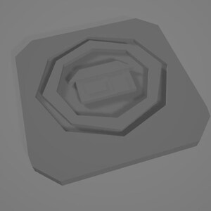 Può includere: Un oggetto grigio di forma ottagonale con cerchi concentrici, creando un effetto a strati. L'oggetto ha un aspetto tridimensionale.