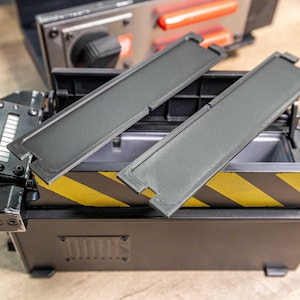 May include: A black box with a yellow and black striped design. The box has two black removable panels. The box is open and the panels are removed.