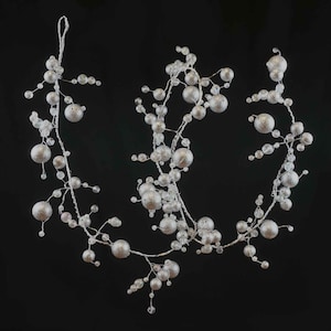 Puede incluir: Una guirnalda plateada con pequeños adornos redondos y cuentas transparentes. La guirnalda es perfecta para añadir un toque de brillo a cualquier decoración navideña.