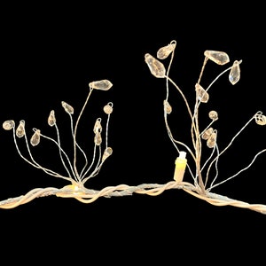 May include: A decorative wire sculpture with crystal accents. The sculpture features two branches with multiple crystal drops hanging from them. The branches are connected by a wire base.
