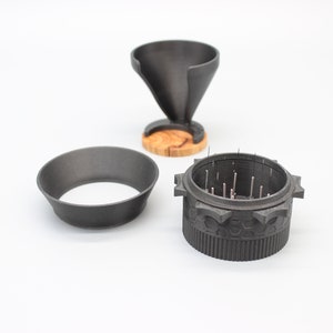 以下が含まれることがあります： 歯車模様の黒いグラインダーと取り外し可能なトップ、木製のベースが付いた黒い漏斗、黒いリング