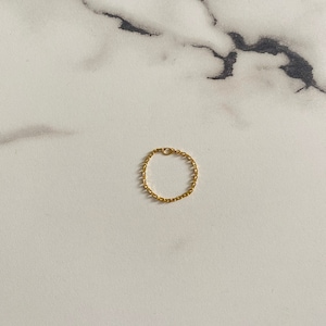 Peut inclure: Une bague en chaîne dorée sur un fond de marbre blanc.