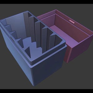 May include: Two-piece storage box set. The larger box is dark blue with a stepped interior, and the smaller box is a muted purple. The boxes are open, revealing their interior design. The set is designed for organizing items.