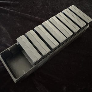 May include: A black plastic storage case with a removable tray. The case is filled with 10 black rectangular containers.