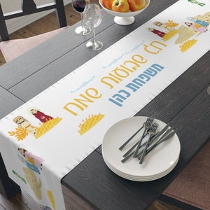 Puede incluir: Un camino de mesa blanco con un diseño azul y amarillo que representa una escena de personas recogiendo trigo. El texto en el camino de mesa dice "La cosecha ya está aquí, el tiempo es maduro".