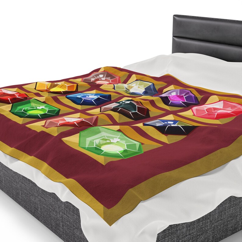K&ouml;nnte beinhalten: Eine weinrote Decke mit einem sich wiederholenden Muster aus bunten, edelsteinartigen Formen. Die Edelsteine sind in verschiedenen Farben, darunter Rot, Gr&uuml;n, Blau und Gelb, auf einem gold-weinroten Hintergrund. Die Decke liegt auf einem Bett.