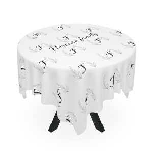 Puede incluir: Mantel blanco redondo con un patrón floral negro y el texto "Florence family" en una fuente cursiva.