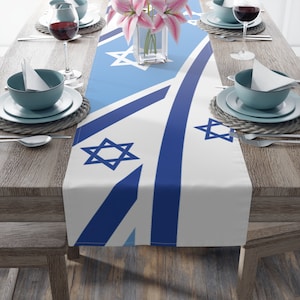 May include: A blue and white table runner with a Star of David pattern. The runner is on a wooden table with two place settings on each side.