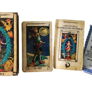 May include: A set of tarot cards with a certificate of authenticity. The cards feature colorful illustrations and are titled "I Tarocchi Della Numerologia Esoterica". The certificate is blue and white with a gold seal.