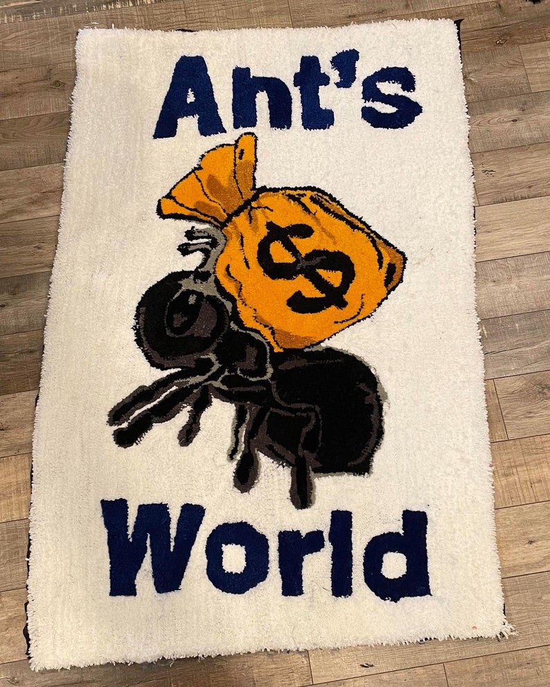 Puede incluir: Una alfombra blanca con una hormiga de dibujos animados azul y negra que lleva una bolsa de dinero amarilla con un signo de d&oacute;lar. El texto "Ant's World" est&aacute; escrito en letras azules debajo de la hormiga.