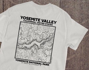 Könnte beinhalten: Weißes T-Shirt mit einem schwarzen topografischen Kartenmotiv auf der Rückseite. Die Karte zeigt das Yosemite Valley, Kalifornien, Vereinigte Staaten. Der Text "Yosemite National Park" und Koordinaten sind unter der Karte gedruckt. Die Vorderseite des Shirts hat ein kleines schwarzes Quadrat mit dem Text "Topo Tops" darin.