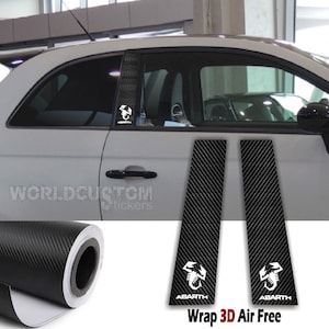 Può includere: Rivestimenti per montanti auto in fibra di carbonio nera con loghi Abarth bianchi. I rivestimenti sono mostrati su un'auto bianca, con un rotolo del materiale visibile. Il testo "Wrap 3D Air Free" è in basso.