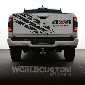 Può includere: Un pick-up bianco con una grafica di battistrada nera e bianca sul portellone. La grafica è sul lato conducente del camion. Il camion ha un adesivo nero "4x4 OFF ROAD" sul portellone. Il camion è parcheggiato su una superficie grigia.