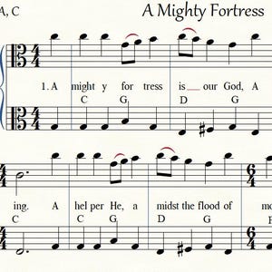 以下が含まれることがあります： マーティン・ルター作曲、リサ・ウィッターズ編曲の「A Mighty Fortress」と題された楽譜。白い背景に黒い音符が記されており、歌詞、コード記号、AとCのヴィオラ記号が含まれています。