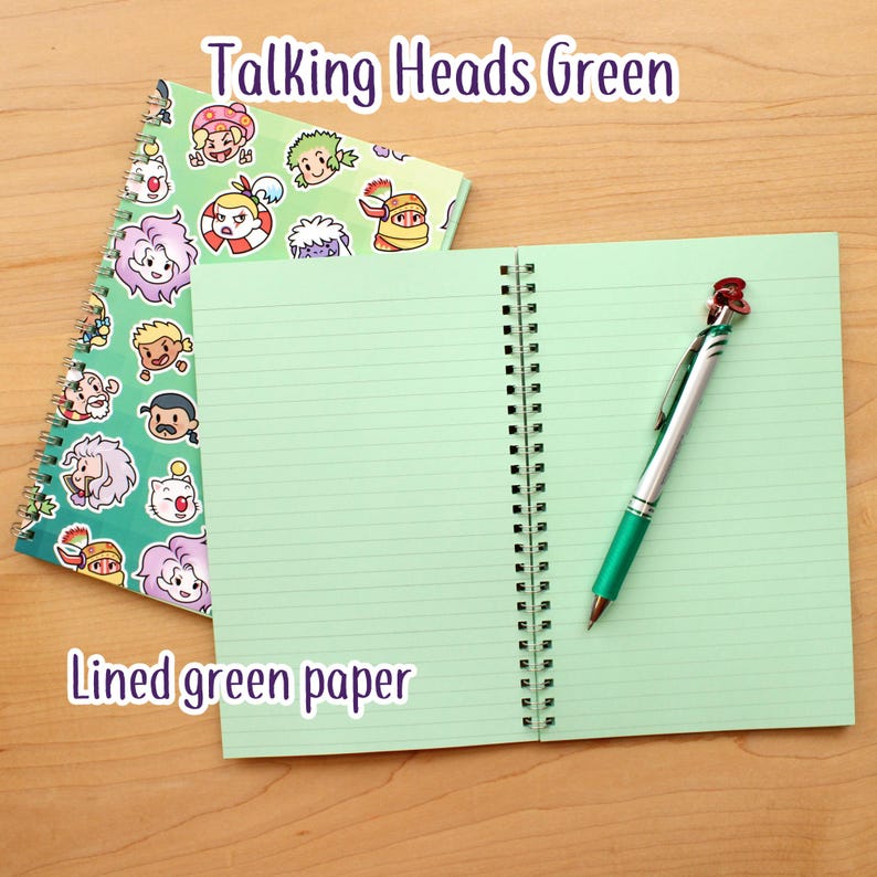 May include: A spiral-bound notebook with a green cover featuring cartoon characters. The notebook is open to reveal lined green paper. A green and silver pen with a red flower design rests on the open pages. The text "Talking Heads Green" and "Lined green paper" are visible.