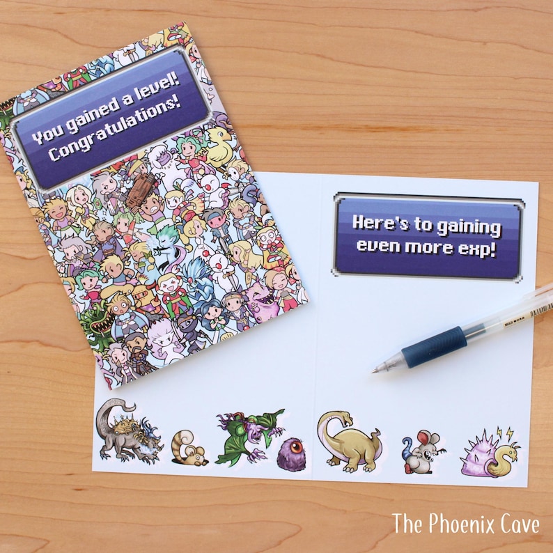 May include: A greeting card with a colorful pixelated design and the text "You gained a level! Congratulations!". The inside reads "Here's to gaining even more exp!" with a pen resting on the page. The Phoenix Cave logo is at the bottom.