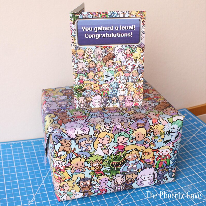 May include: A gift box and greeting card featuring a colorful cartoon character design. The card reads "You gained a level! Congratulations!" The gift box and card are covered in a variety of cartoon characters.