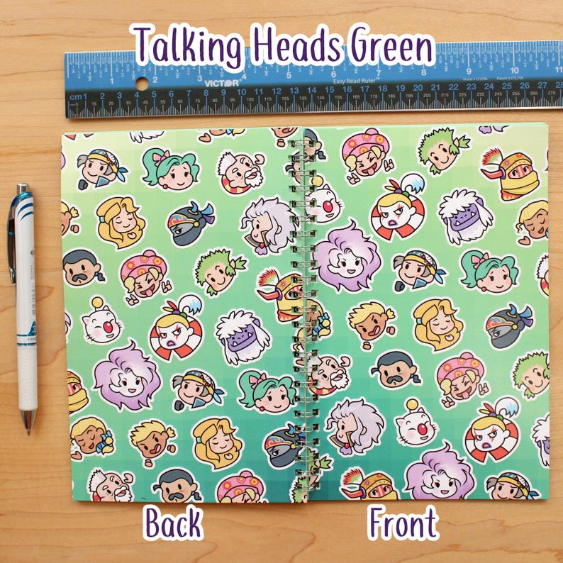 May include: A spiral-bound notebook with a green gradient background and a repeating pattern of cartoon faces. The notebook is labeled "Talking Heads Green" and has "Back" and "Front" labels. A ruler is placed above the notebook. A pen is on the left.