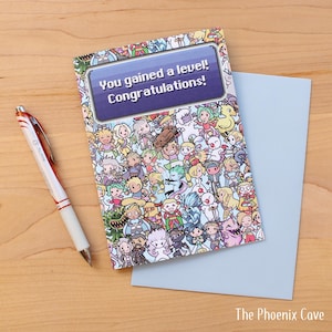 May include: Greeting card with a colorful cartoon design and the text "You gained a level! Congratulations!" A light blue envelope and a pen with red accents are next to the card. The Phoenix Cave logo is in the bottom right corner.