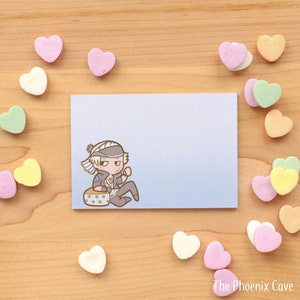 May include: A blue and white striped notecard with a cartoon illustration of a person wearing a striped hat and sitting on a drum. The person is wearing a blue shirt with a white design and black pants.